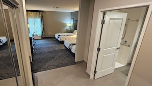 Une chambre d’hôtel avec deux lits, un sol recouvert de moquette, une porte et un espace douche.