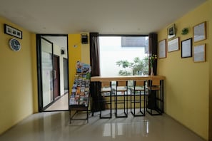 Cozy seating area with a wooden table and chairs, wall-mounted clock, and framed documents.
