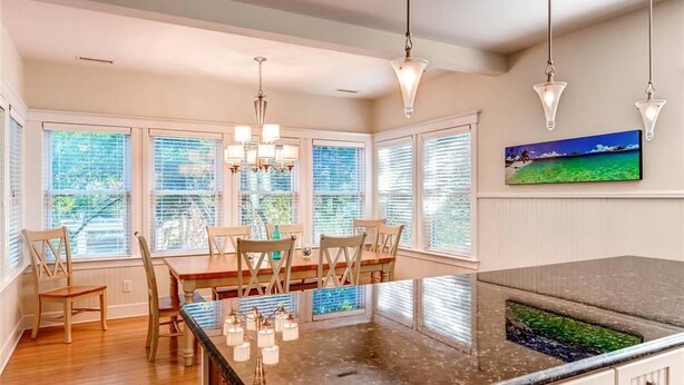 A kitchen with a central island, wooden chairs, and pendant lighting.