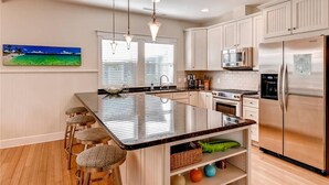 A modern kitchen with a central island, stainless steel appliances, and bar stools.
