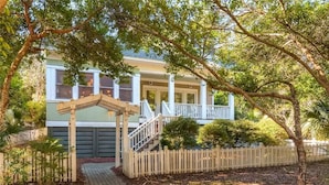 A two-story house with a covered porch, a staircase leading to the upper floor, and a picket fence surrounding the property.