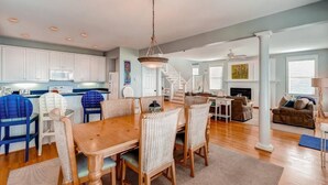 A spacious living area with a dining table and chairs, a staircase, and a fireplace. - Footprints In The Sand 4 Bedroom Holiday Home By Bald Head Island (Bald Head Island)