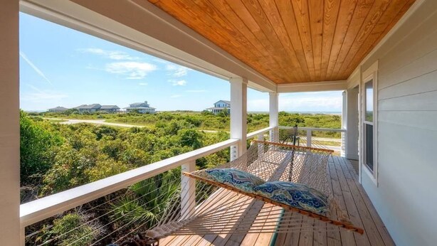 A wooden deck with a hammock and a view of a coastal landscape. - Hat Trick 4 Bedroom Holiday Home By Bald Head Island (Bald Head Island)