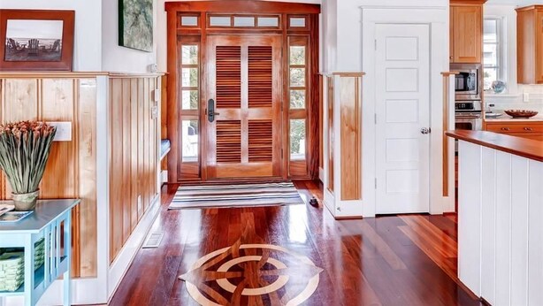 A hallway with wooden doors, a kitchen area with cabinets, and a dining table. - Island Belle 4 Bedroom Holiday Home By Bald Head Island (Bald Head Island)