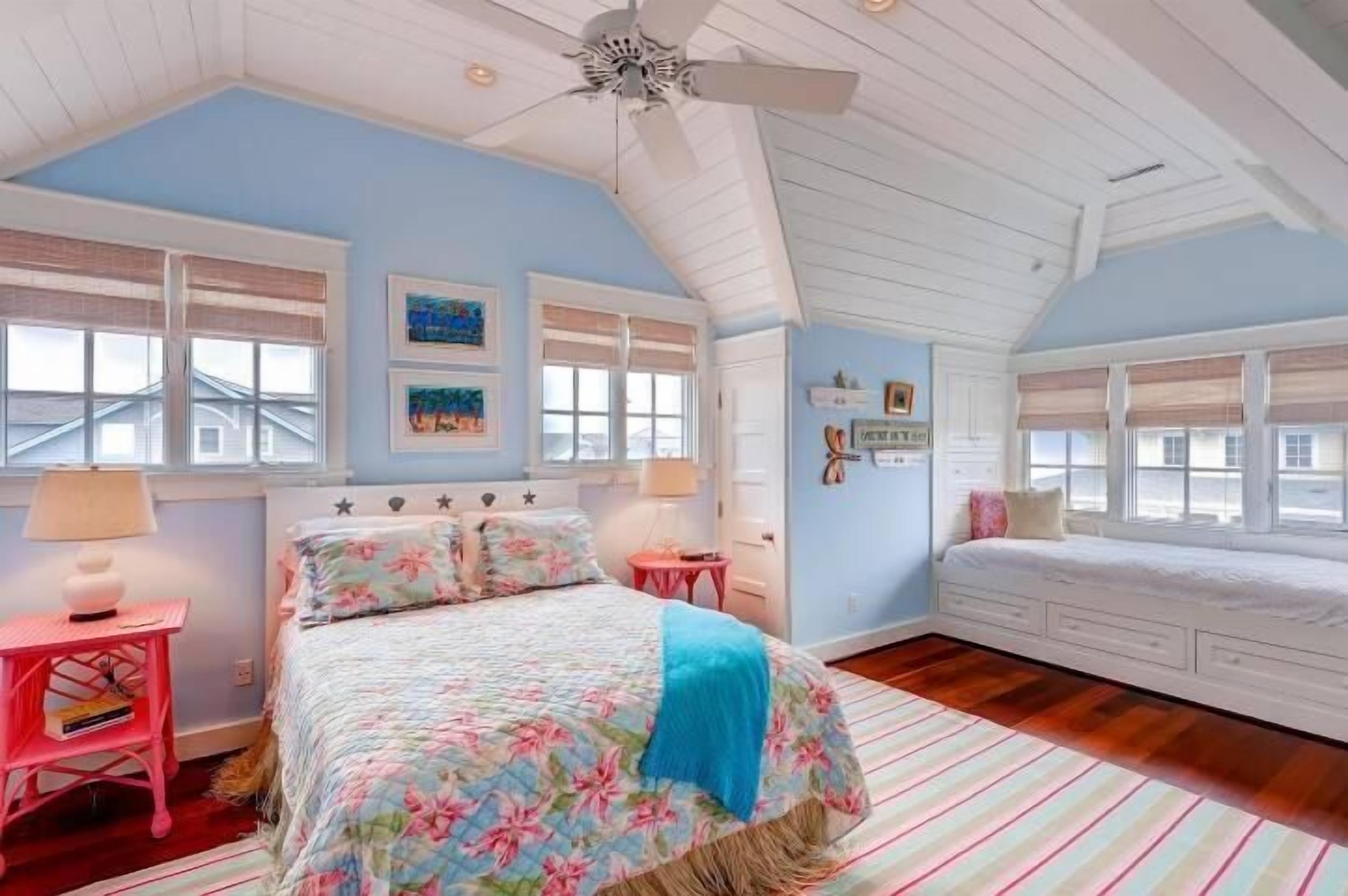 A bedroom with a bed, a nightstand, a dresser, and a window with blinds.