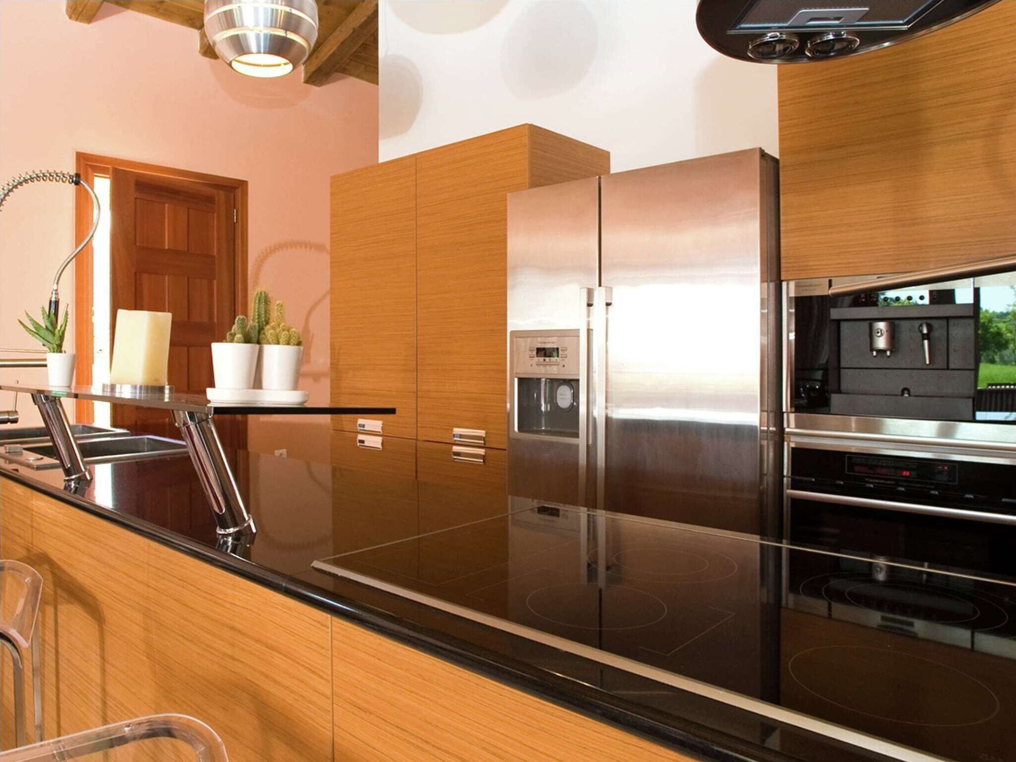 Uma cozinha moderna com eletrodomésticos de aço inoxidável, armários de madeira e bancada preta.