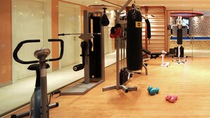 Une salle de sport équipée de matériel d’exercice, d’un sac de frappe et d’haltères.