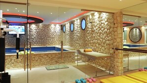 Une salle de sport avec des murs en pierre, une table de massage et du matériel d’exercice.