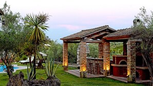 Un espace extérieur aménagé avec un barbecue en briques, des piliers en pierre et une pergola.