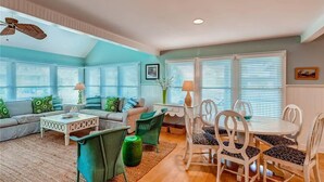 A spacious living room with a sofa set, a coffee table, and a dining area with chairs and a table. - Island Retreat 4 Bedroom Holiday Home By Bald Head Island (Bald Head Island)
