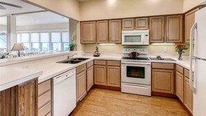 A modern kitchen with wooden cabinets, a microwave, an oven, and a dishwasher. - JJ s Hideaway 4 Bedroom Holiday Home By Bald Head Island (Bald Head Island)