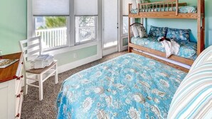 A bedroom with bunk beds, a chair, a desk, and a window with blinds. - JJ s Hideaway 4 Bedroom Holiday Home By Bald Head Island (Bald Head Island)