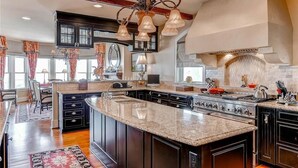A spacious kitchen with dark cabinetry, a large island, and a built-in oven. - Loggerhead Lady 4 Bedroom Holiday Home By Bald Head Island (Bald Head Island)