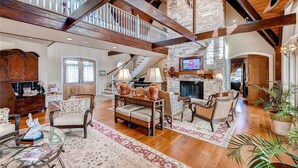 A spacious living room with a stone fireplace, wooden beams, and a high ceiling. - Loggerhead Lady 4 Bedroom Holiday Home By Bald Head Island (Bald Head Island)