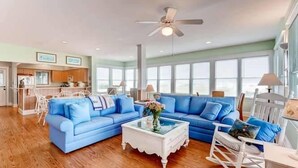 A spacious living room with a blue sectional sofa, a white coffee table, and a rocking chair. - Paradise 3 Bedroom Holiday Home By Bald Head Island (Bald Head Island)