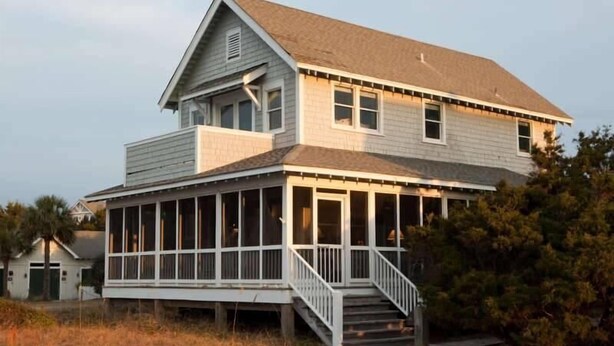 A two-story house with a porch and a staircase leading to the entrance. - Purrfect Paws 2 Bedroom Holiday Home By Bald Head Island (Bald Head Island)