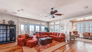 A spacious living room with a large sectional sofa, a wooden coffee table, and a ceiling fan. - Summer Island 6 Bedroom Holiday Home By Bald Head Island (Bald Head Island)