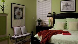 A bedroom with a bed, a nightstand, a chair, and a window with blinds. - Summer House 4 Bedroom Holiday Home By Bald Head Island (Bald Head Island)
