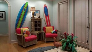 A room with two wicker chairs, a lamp, a surfboard, and a potted plant. - Summer House 4 Bedroom Holiday Home By Bald Head Island (Bald Head Island)