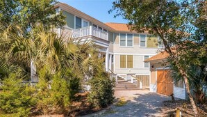 A two-story building with a covered porch and a gravel driveway. - Tiburon Marsh 4 Bedroom Holiday Home By Bald Head Island (Bald Head Island)