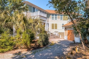 A two-story building with a covered porch and a gravel driveway.
