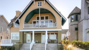 A two-story house with a balcony, a front porch, and a staircase leading to the entrance. - Twin Peaks 3 Bedroom Holiday Home By Bald Head Island (Bald Head Island)