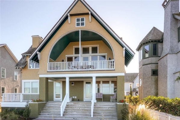 A two-story house with a balcony, a front porch, and a staircase leading to the entrance.