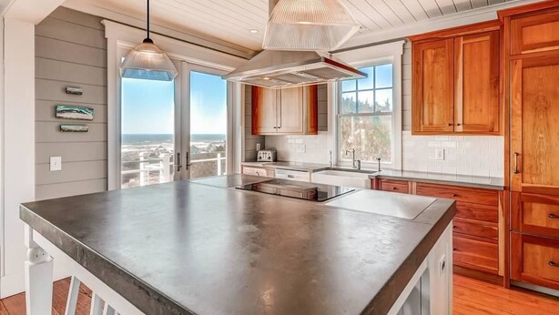 A modern kitchen with a large island, wooden cabinets, and pendant lighting. - Watch Hill 5 Bedroom Holiday Home By Bald Head Island (Bald Head Island)
