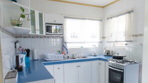 Une cuisine avec des meubles blancs, un plan de travail bleu, un four à micro-ondes, un évier et une cuisinière.