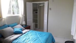 Une chambre à coucher comprenant un lit, une table de chevet, une commode, une armoire et une fenêtre.