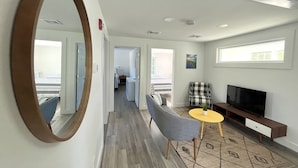 A hotel room with a large mirror, a TV, a sofa, a small table with a plant, and a patterned rug. - Kingfisher Lodging (Dennis)