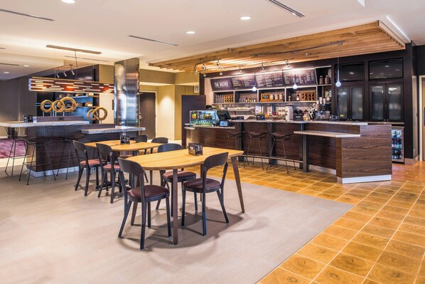A modern restaurant with a bar area, wooden flooring, and a seating arrangement with tables and chairs. - Courtyard by Marriott Detroit Farmington (Farmington Hills)