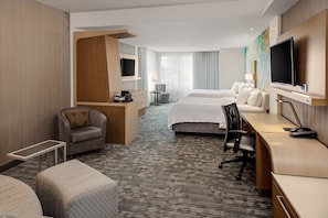 A hotel room with a bed, a desk, a chair, a TV, and a small table. - Courtyard by Marriott Detroit Farmington (Farmington Hills)