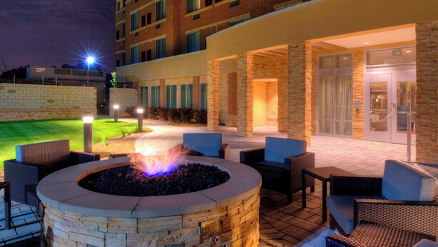 A courtyard with a fire pit, outdoor seating, and a building entrance. - Courtyard by Marriott Detroit Farmington (Farmington Hills)