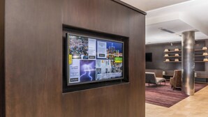 A modern hotel lobby with a digital display board, comfortable seating, and a well-organized reception area. - Courtyard by Marriott Detroit Farmington (Farmington Hills)