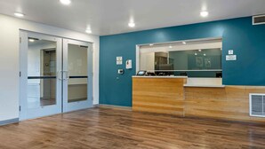 Un espace d’accueil avec un comptoir en bois, des portes en verre et un mur bleu.