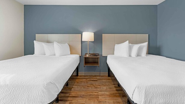 Une chambre d’hôtel avec deux lits, une table de chevet et une lampe.
