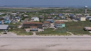A coastal area with a beach, a road, and several buildings including a large multi-story structure. - Little Shell 152 (Port Aransas)