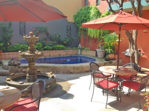 A patio area with a fountain, a pool, and outdoor seating with umbrellas. - Hotel Casa de Leyendas (Mazatlán)