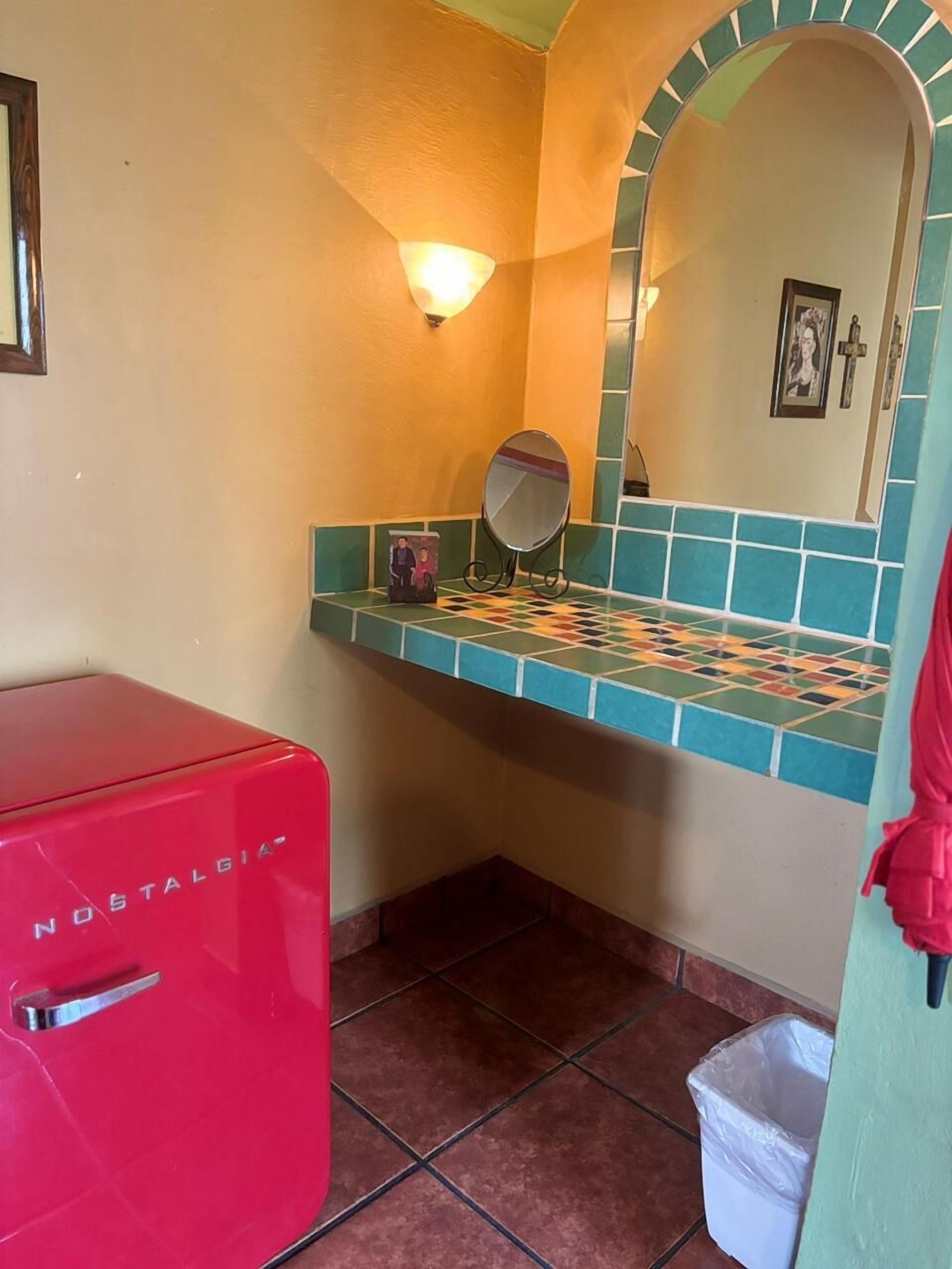 Ein Badezimmer mit Fliesenboden, roten Geräten, einem Spiegel und einer Wandleuchte.
