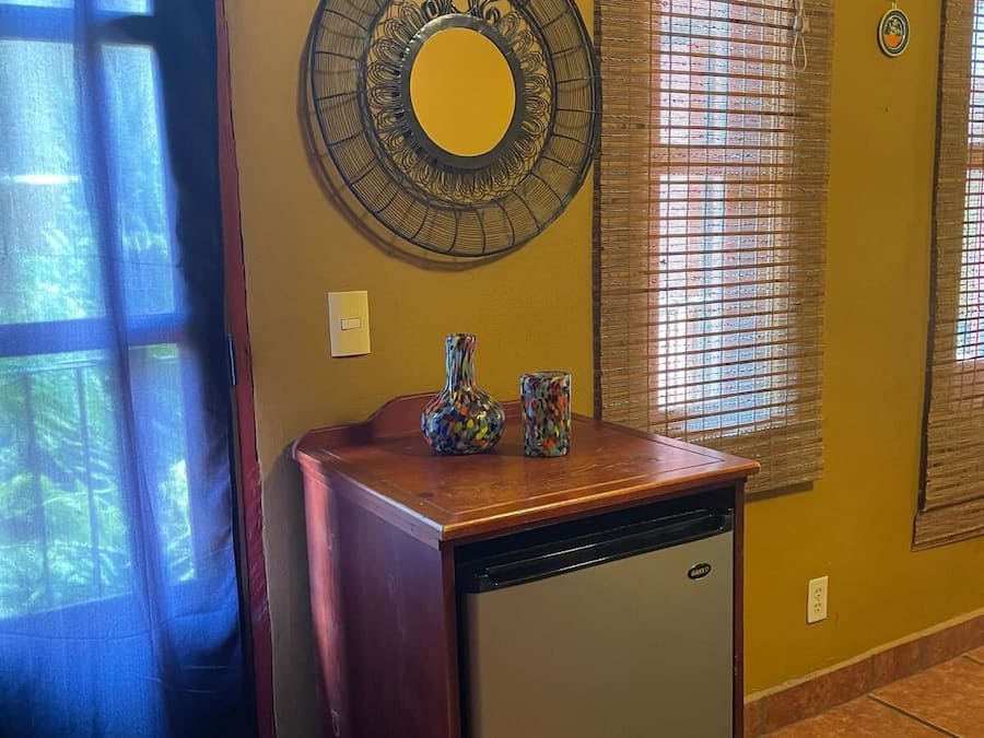 Una cocina compacta con un refrigerador empotrado, un armario de madera y un espejo decorativo en la pared.