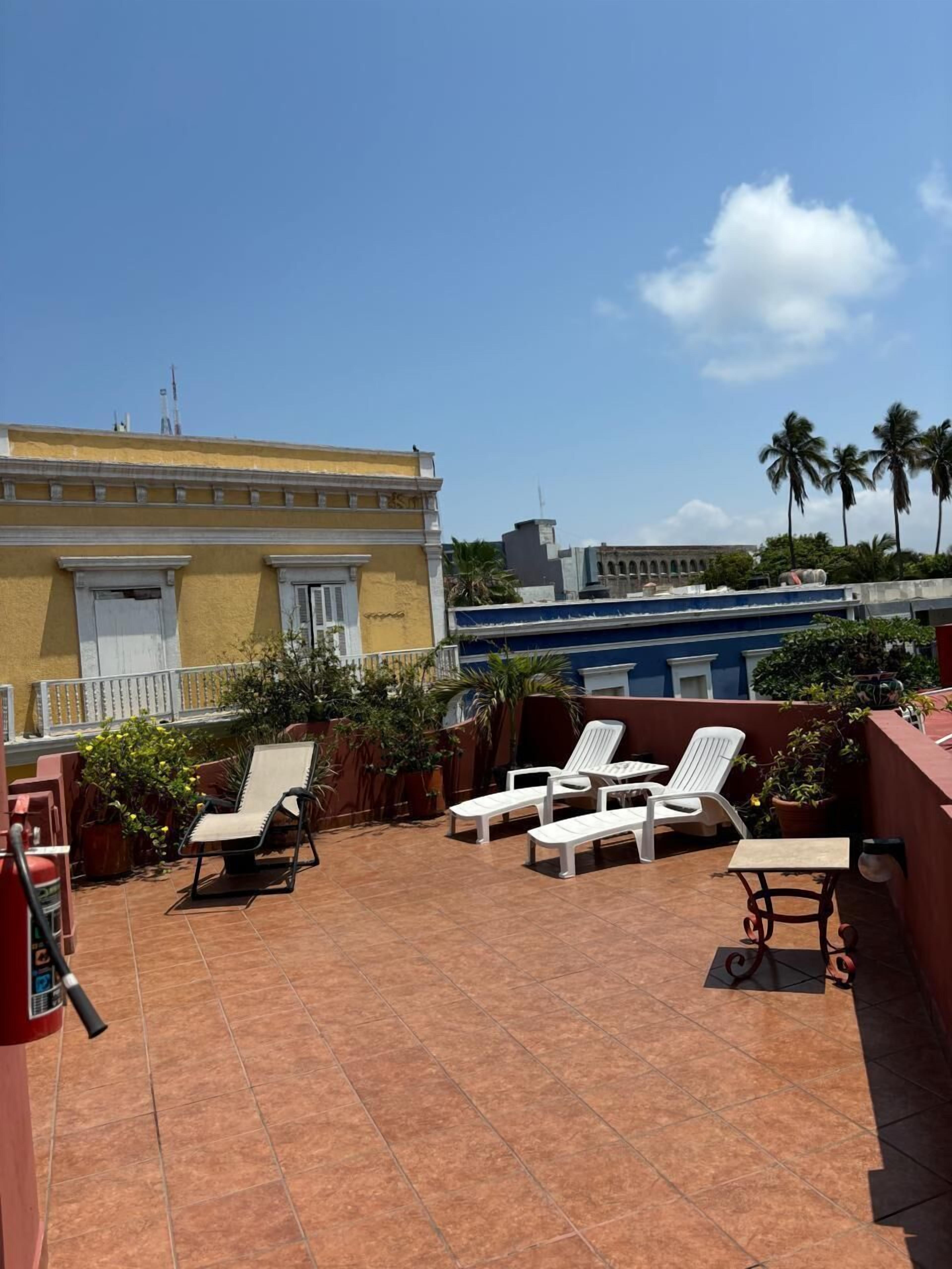 Una terraza en la azotea con sillones, una mesa y plantas en macetas.