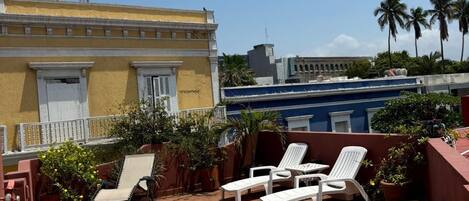 Una terraza en la azotea con sillones, una mesa y plantas en macetas.