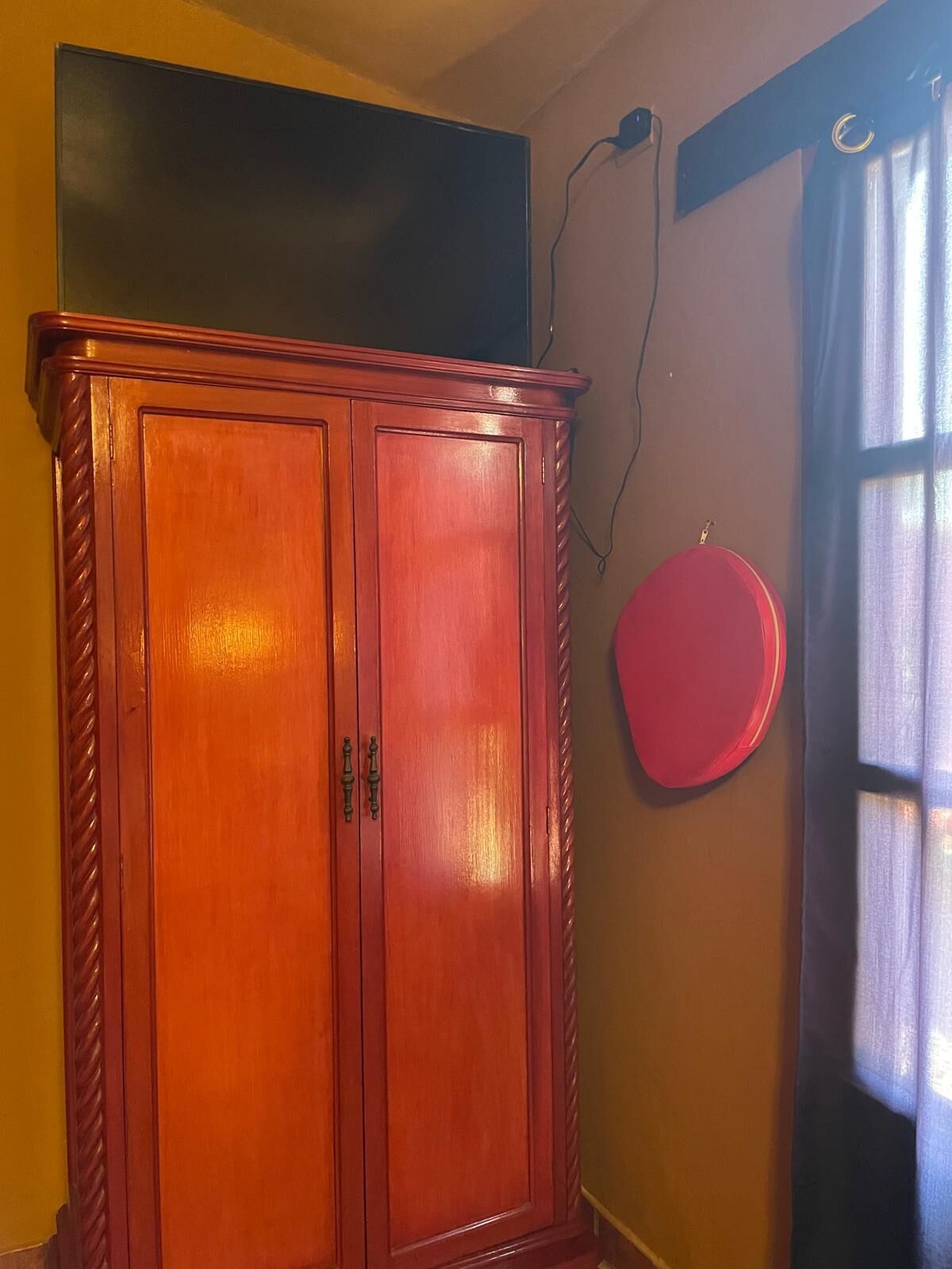 A wooden wardrobe with two doors, a blackboard above it, and a red circular object on the wall.