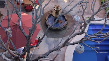 Un patio con una fuente, asientos exteriores y una piscina azul.