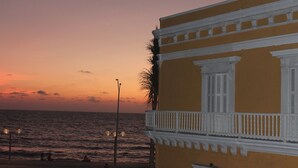 A coastal building with a balcony overlooking the sea during sunset.