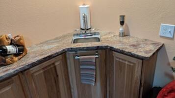 A corner kitchen with wooden cabinets, a granite countertop, a sink, and a towel rack.