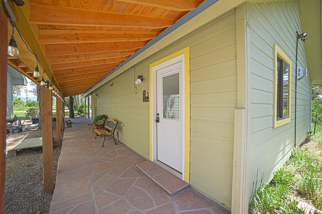 A covered porch with stone flooring, a door, and a small bench.