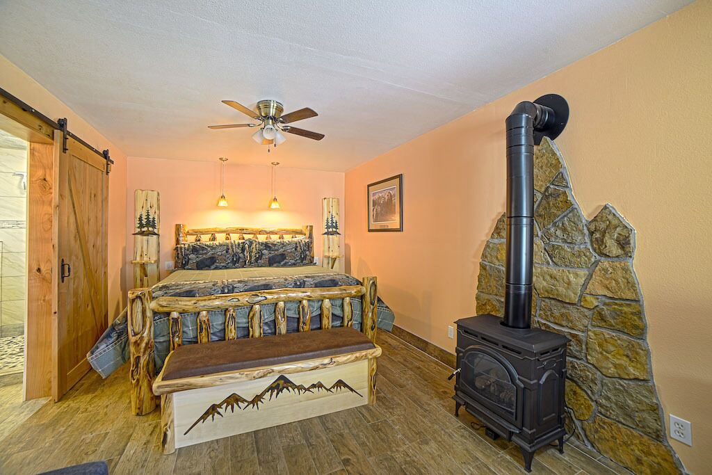 Ein Schlafzimmer mit einem Bett, einer Bank, einem Deckenventilator, einer Steinwand und einem Kaminofen.
