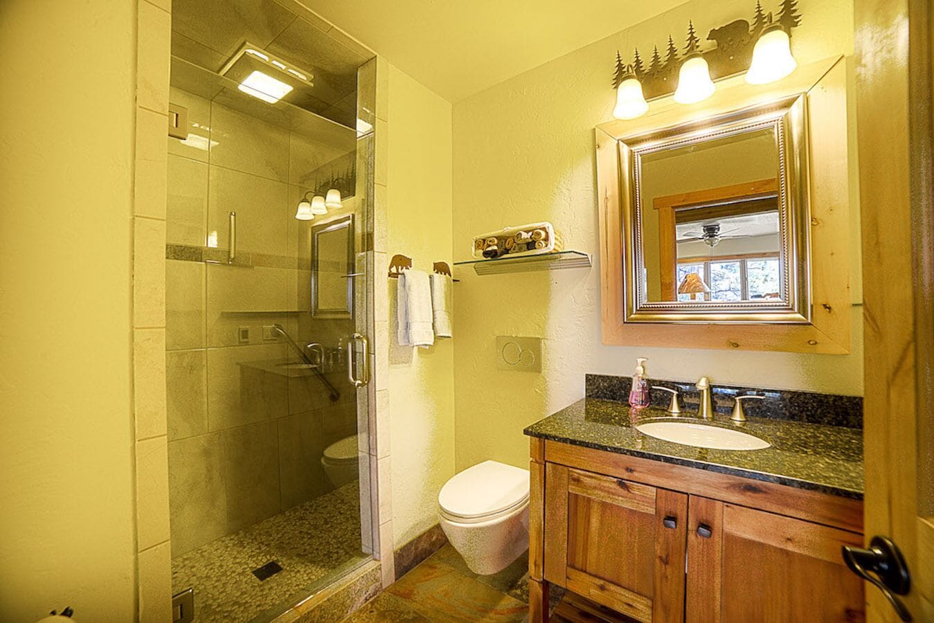 Un baño con ducha acristalada, inodoro y lavabo con mueble de madera.